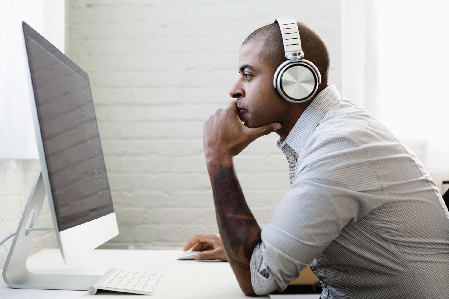 Man wearing headphones using a Mac computer
