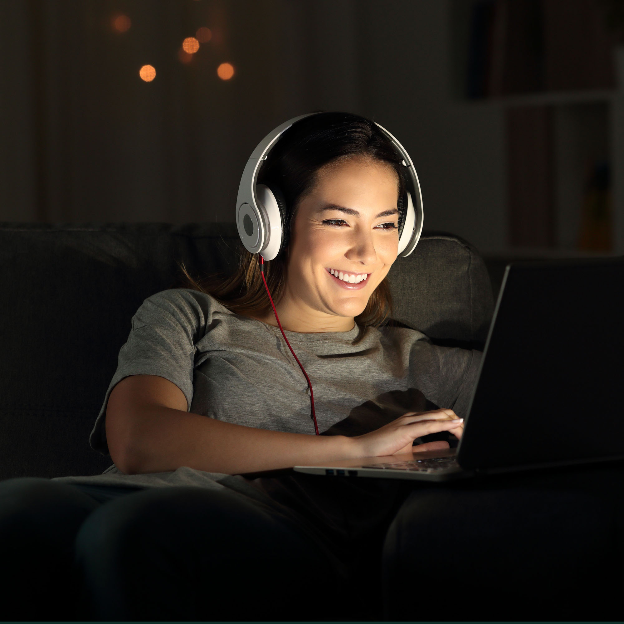 Young women wearing large headphones watching streamed content on her laptop