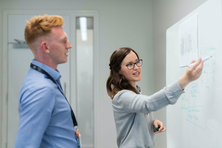 Young man and woman in front of whiteboard