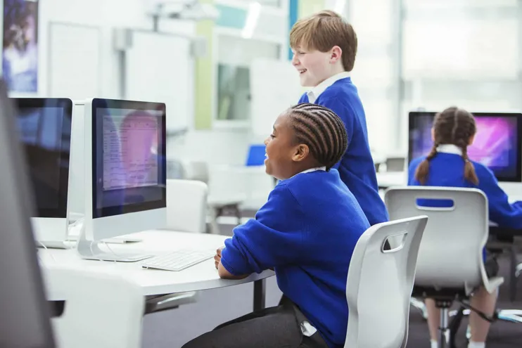 Two School Children Laughing Using A Computer