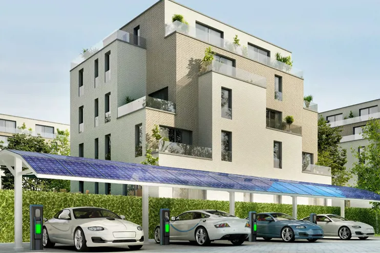 A row of electric cars charging in front of a modern apartment block