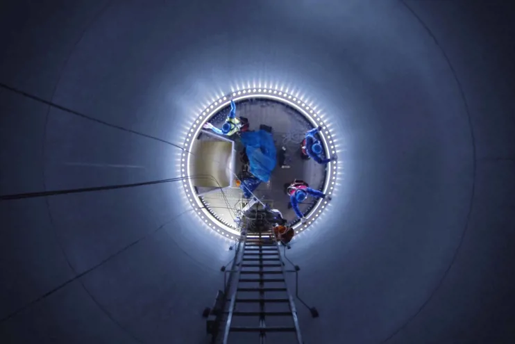 Low angle view of workers in illuminated wind turbine at night